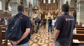 Menschen mit Malteser Shirt stehen in einer Kirche