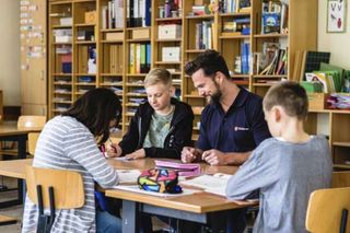 Mitarbeiter unterstützt Kind in Schule