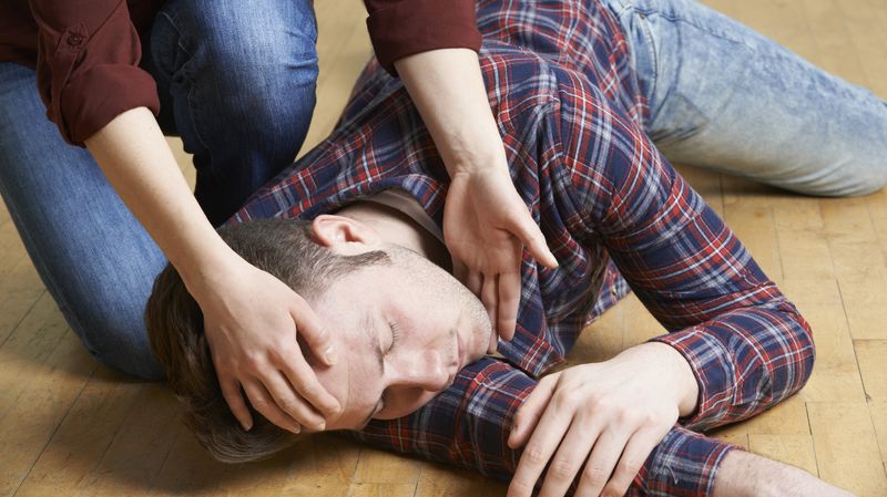 Ein junger Mann, der mit geschlossenen Augen auf dem Boden liegt.