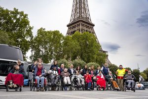 Eine Gruppe von Menschen, ein Teil davon in Rollstühlen, vor dem Pariser Eiffelturm