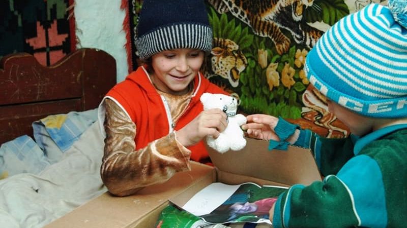 Zwei kleine Jungen packen ein Geschenk aus