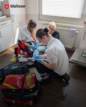 Zwei Sanitäterinnen kümmern sich um eine Patientin, eine dokumentiert Werte, die andere betreut die Patientin
