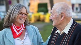 Helferin der Malteser mit einem an Demenz erkranktem Mann im Garten. 