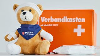 Erste-Hilfe-Verbandskasten mit Teddy, der verbunden und gepflastert ist