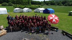 Gruppenfoto von ca. 50 Jugendlichen und Gruppenleitungen der Malteser Jugend, welches mit einer Drohne aufgenommen wurde. Im Hintergrund der Gruppe sieht man 5 Großzelte, in denen die Personen während des Zeltlagers geschlafen haben. 