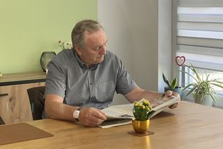 Ein Senior mit einem Hausnotruf-Armband beim Zeitunglesen