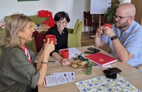 Menschen sitzen am Tisch und unterhalten sich.