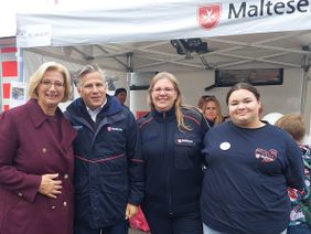 Ein Malteser und drei Frauen, zwei davon im Malteser Outfit