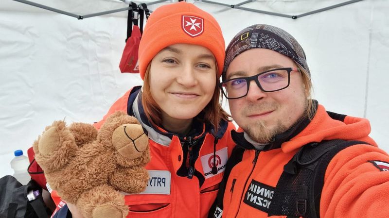 Eine junge Frau und ein junger Mann in Einsatzkleidung der Malteser mit einem Teddy