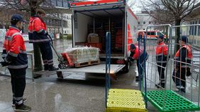 Menschen in Malteser-Kleidung laden einen Lkw aus.