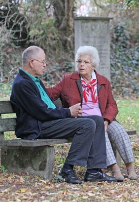 Zwei Menschen sitzen auf einer Parkbank und reden miteinander. Foto: Malteser