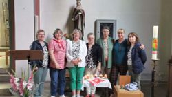 Frauen stehen in einer Kirche vor einem Altar.