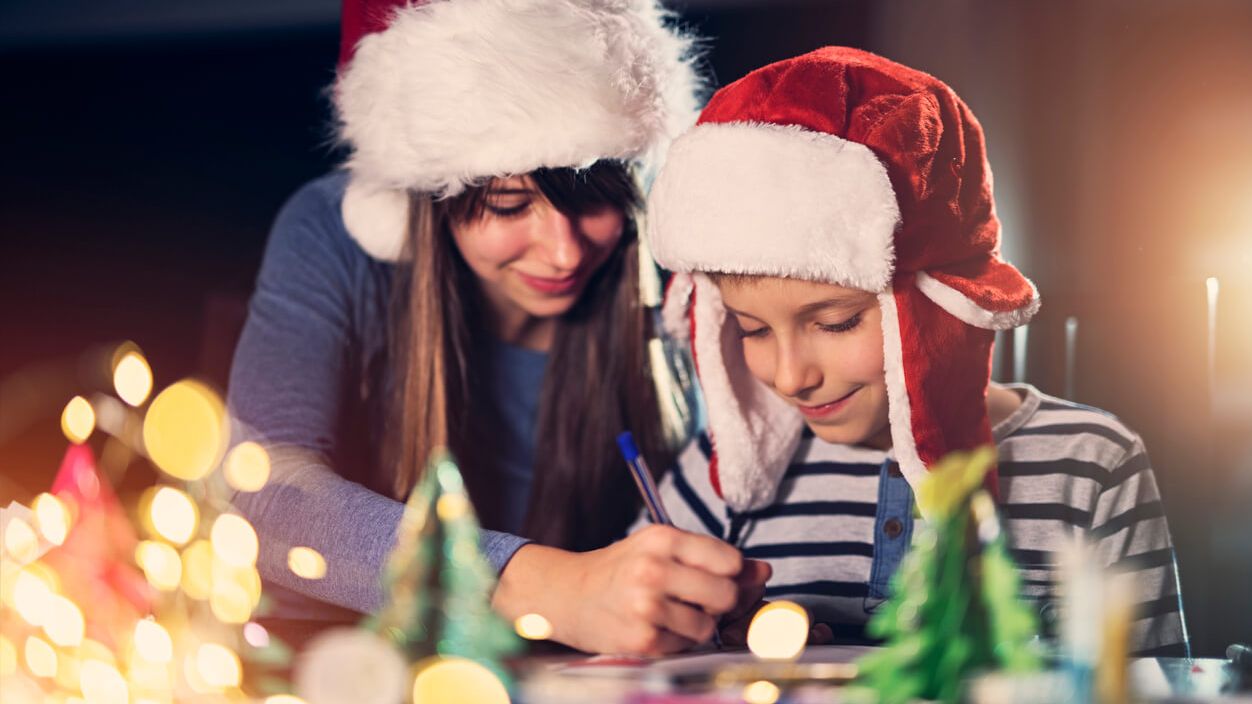 Junge Frau malt mit einem Kind Weihnachtsbilder