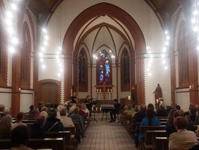 Das Foto zeigt den Innenraum der Sankt Josef Kirche. Musiker geben ein Konzert. 