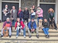 10 Mensch-Hund-Teams vom Malteser Hilfsdienst e.V. Neustadt sitzen auf einer Treppe (Quelle: Malteser Neustadt)