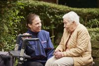 Eine ehrenamtliche Malteserin begleitet eine ältere Dame auf dem Friedhof. 