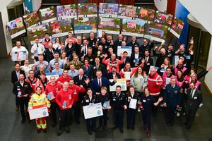 Viele Menschen mit freudigen Gesichtern winken in die Kamera.