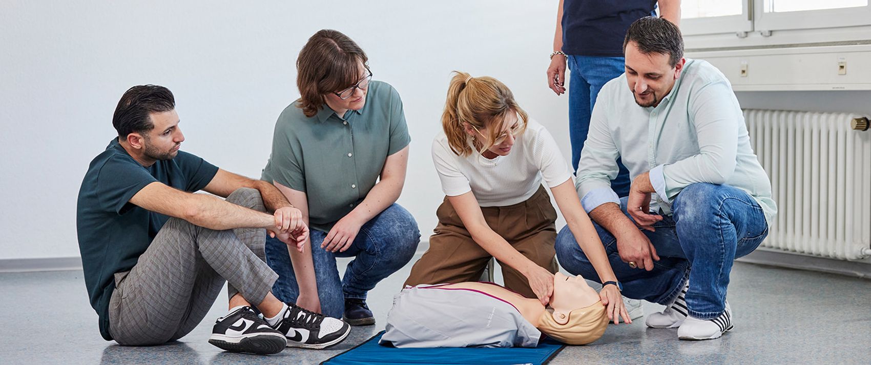 Beim Erste-Hilfe-Kurs der Malteser: Eine Gruppe übt an einer Puppe die Herzdruckmassage.