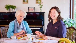 Eine junge und eine ältere Frau sitzen am Tisch und essen Kuchen.