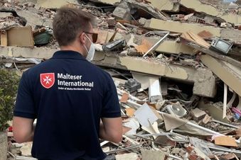 Ein Mann steht vor einem eingestürzten Haus. Foto: Malteser International