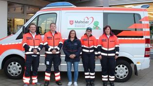 Menschen in Malteser Einsatzkleidung vor dem Malteser Herzenswunschkrankenwagen