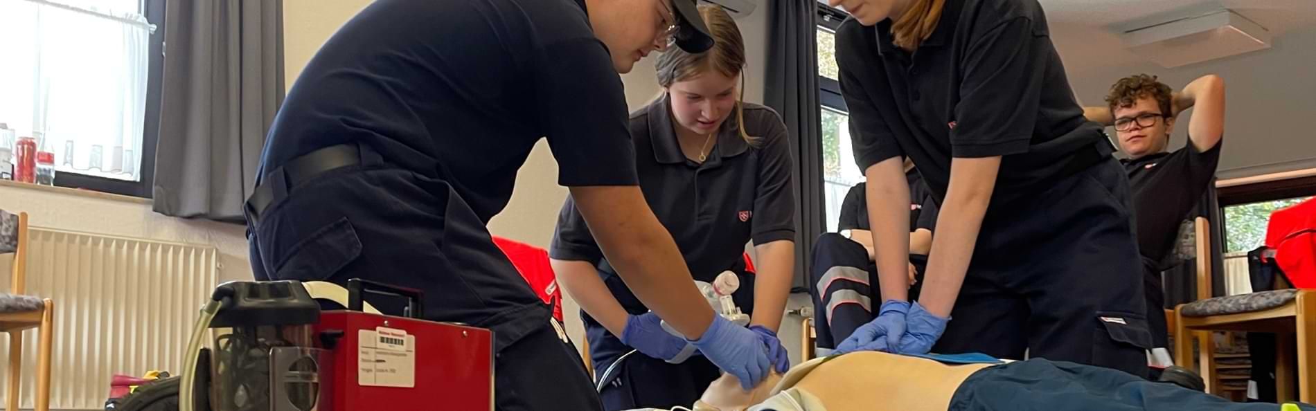 Junge Menschen üben an einer Erste-Hilfe-Puppe