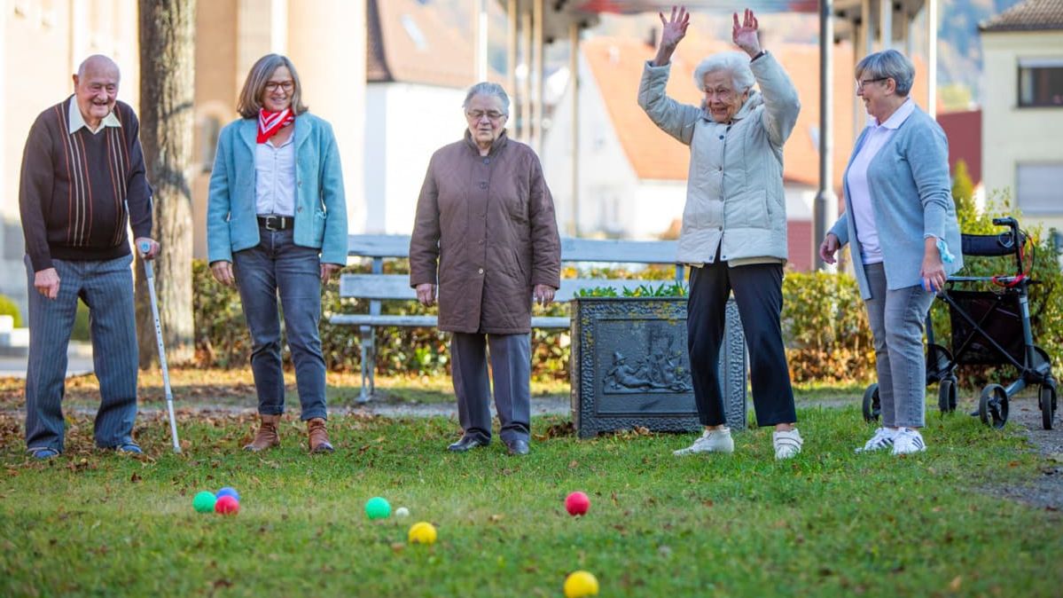 Mehrere ältere Menschen haben Spaß beim Boccia spielen.