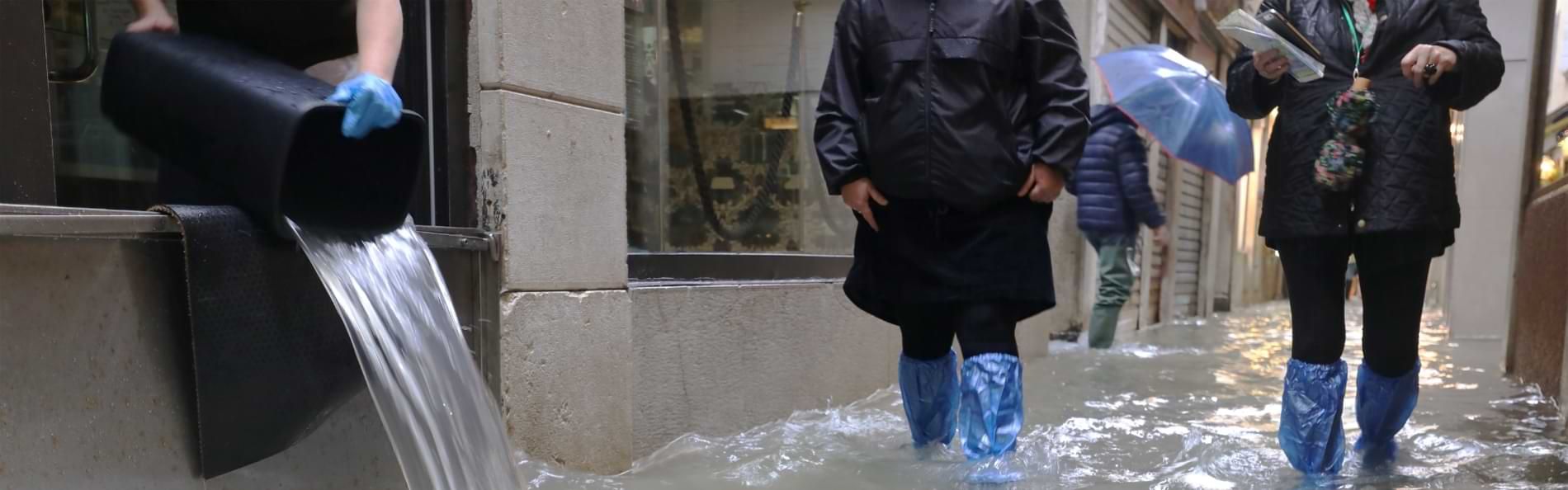 Menschen bei Hochwasser in einer kleinen Seitenstraße.