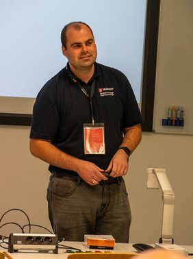 Ein Mann in Malteser Polo-Shirt vor einer Präsentation