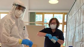 Zwei Menschen mit Schutzkleidung in einem Raum.