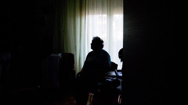 Eine alte Frau in einem dunklen Zimmer.