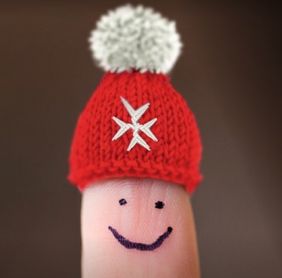 Ein Finger, auf den ein lachendes Gesicht gemalt ist, trägt eine rote Mütze