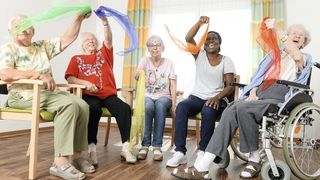 Fünf Frauen winken mit Tüchern und sitzen auf Stühlen.