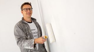 Ein Mann streicht beim Malteser Social Day in Mainz eine Wand weiß.