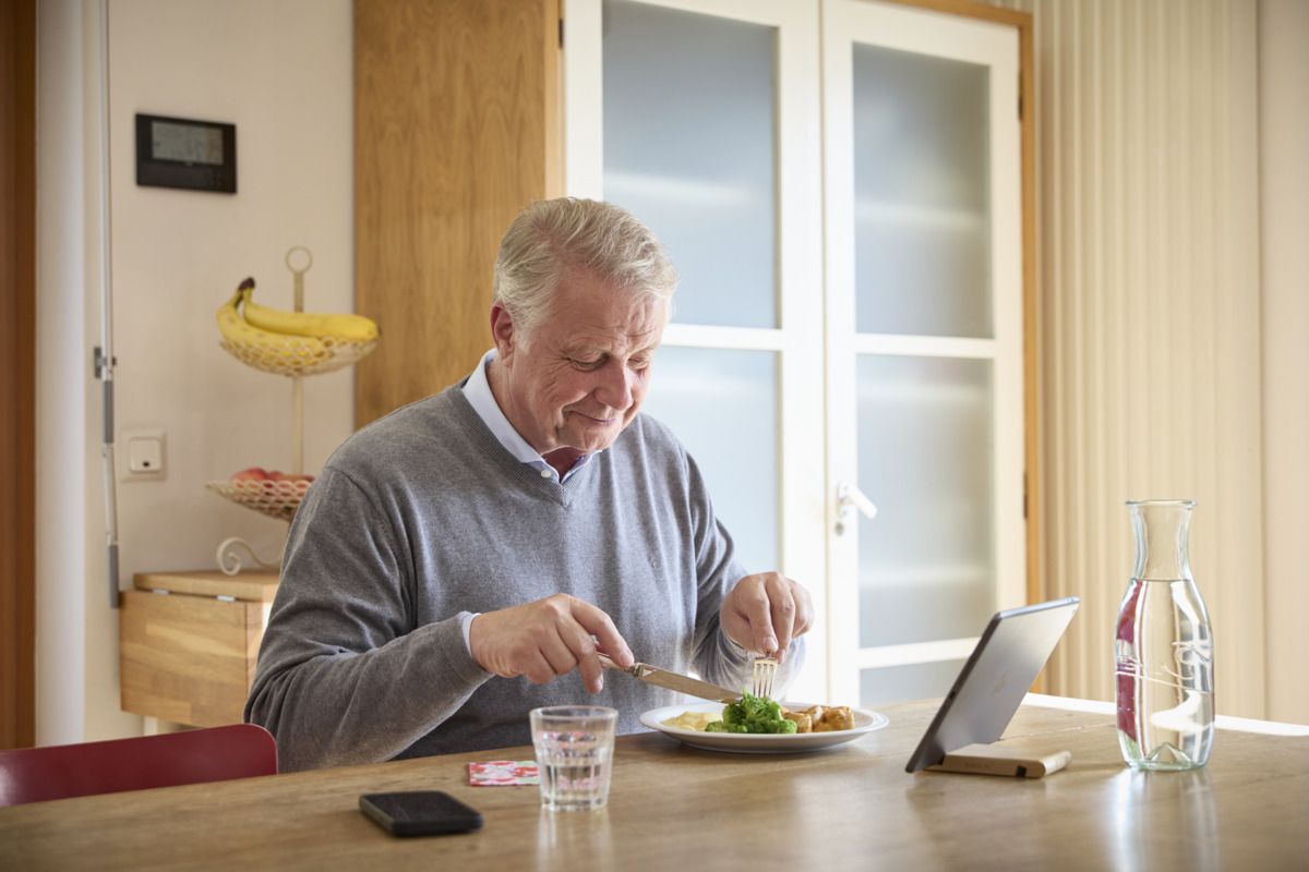 Ein Mann isst zuhause ein Gericht des Menüservice Wochenkartons.