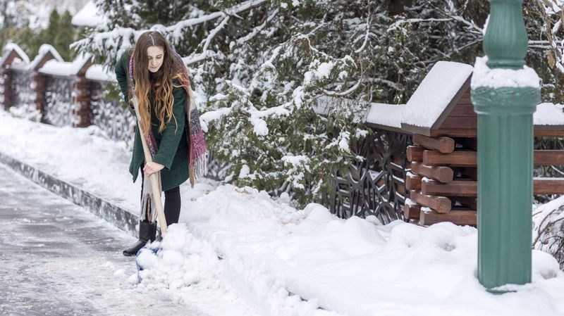 Junge Frau beim Schnee schippen