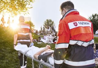 Malteser Sanitätsdienst: Sanitäter transportieren Person auf einer Trage.