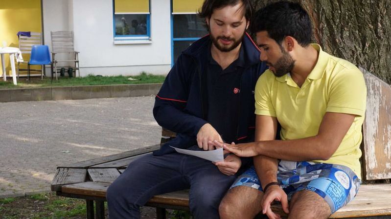 Zwei junge Männer auf einer Bank in einem Innenhof