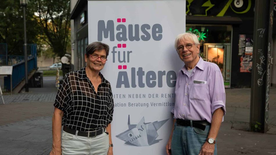 Seniorenpaar wirbt für das Straßenplakat: Mäuse für Ältere.