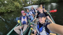 sieben Jugendliche und Gruppenleitungen, die in zwei Kanus auf der Lahn sitzen und freudig in die Kamera lächeln