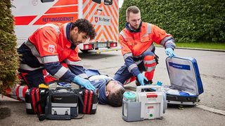 Mitarbeiter im Malteser Rettungsdienst kümmern sich um einen Verletzten auf der Straße.