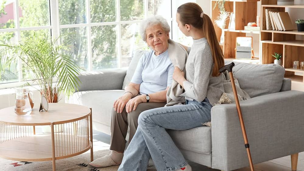 Eine junge Frau sitzt mit einer älteren Frau auf der Couch.