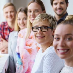 Gruppe von Personen steht nebeneinander und blickt in Richtung Kamera.