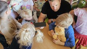 Ein Mann hält ein Handy. Ein Kind lernt, einen Notruf abzusetzen.