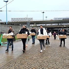 Junge Männer tragen Kisten. Darin sind gefüllte Beutel.