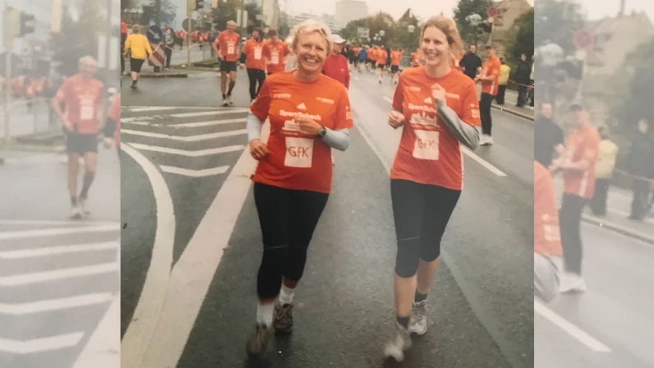 Zwei Frauen in orangefarbenen Trikots bei einer Laufveranstaltung.