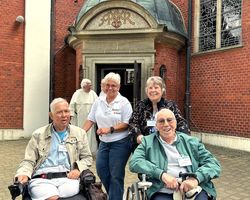 Personen stehend und sitzend, Kleidung, Rollstühle