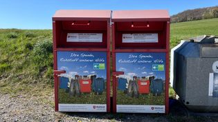 Zwei Altkleidercontainer der Malteser. Im Hintergrund blauer Himmel.