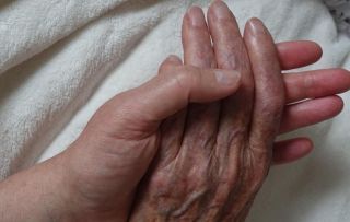 Eine junge Hand hält eine alte Hand