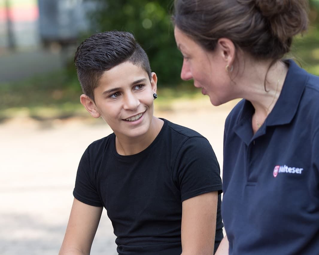 Ehrenamtliche Mitarbeiterin der Malteser spricht mit einem Jungen.